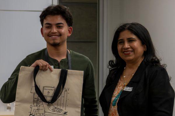 male student holding a beige canvas tote bag with line art
