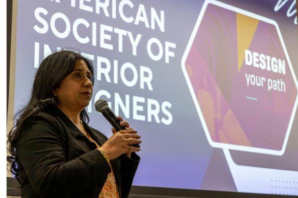 woman with long dark hair holding a microphone presenting american society of interior designers slide deck
