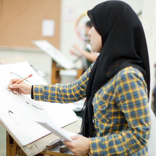 Student drawing on canvas in classroom