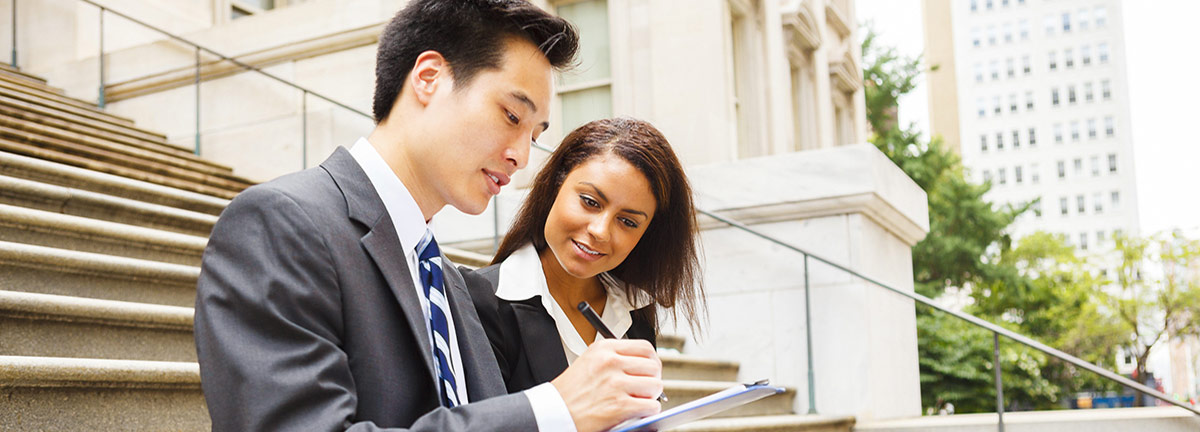 Man and woman business professionals with clipboard sitting on steps