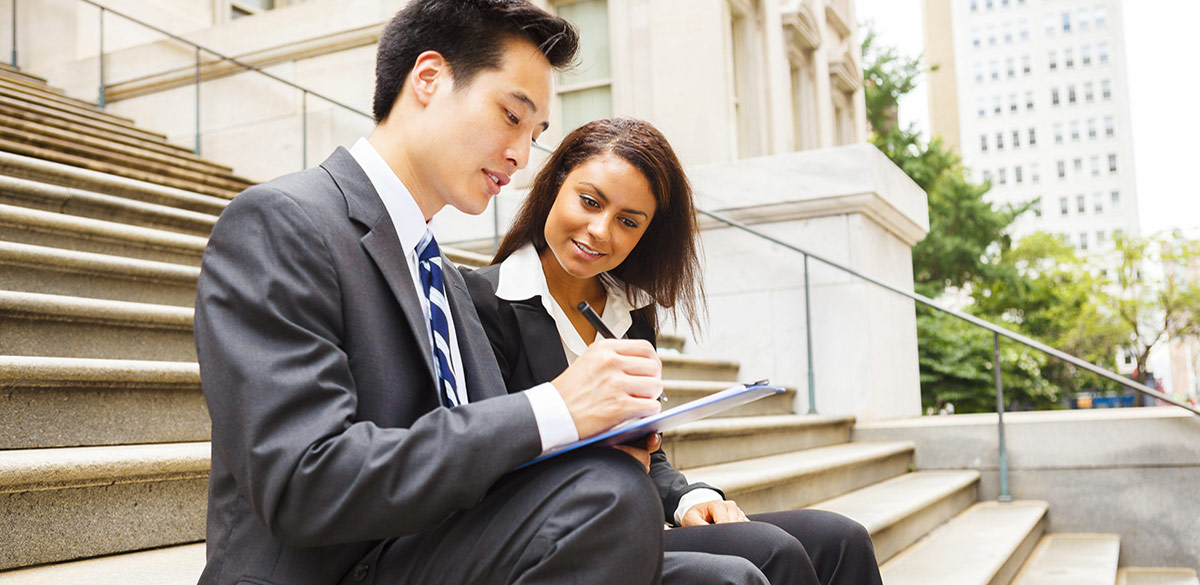 Man and woman business professionals with clipboard sitting on steps