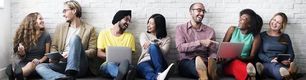 Diverse students against wall laughing at laptop