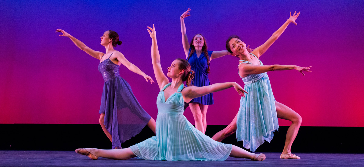Four women in blue dresses dancing in front of gradient background Four women in blue dresses dancing in front of gradient background