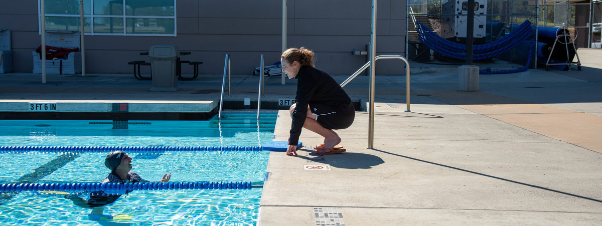 Aquatics instructor coaching student in pool Aquatics instructor coaching student in pool