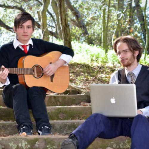 Two music students on stairs guitar and laptop