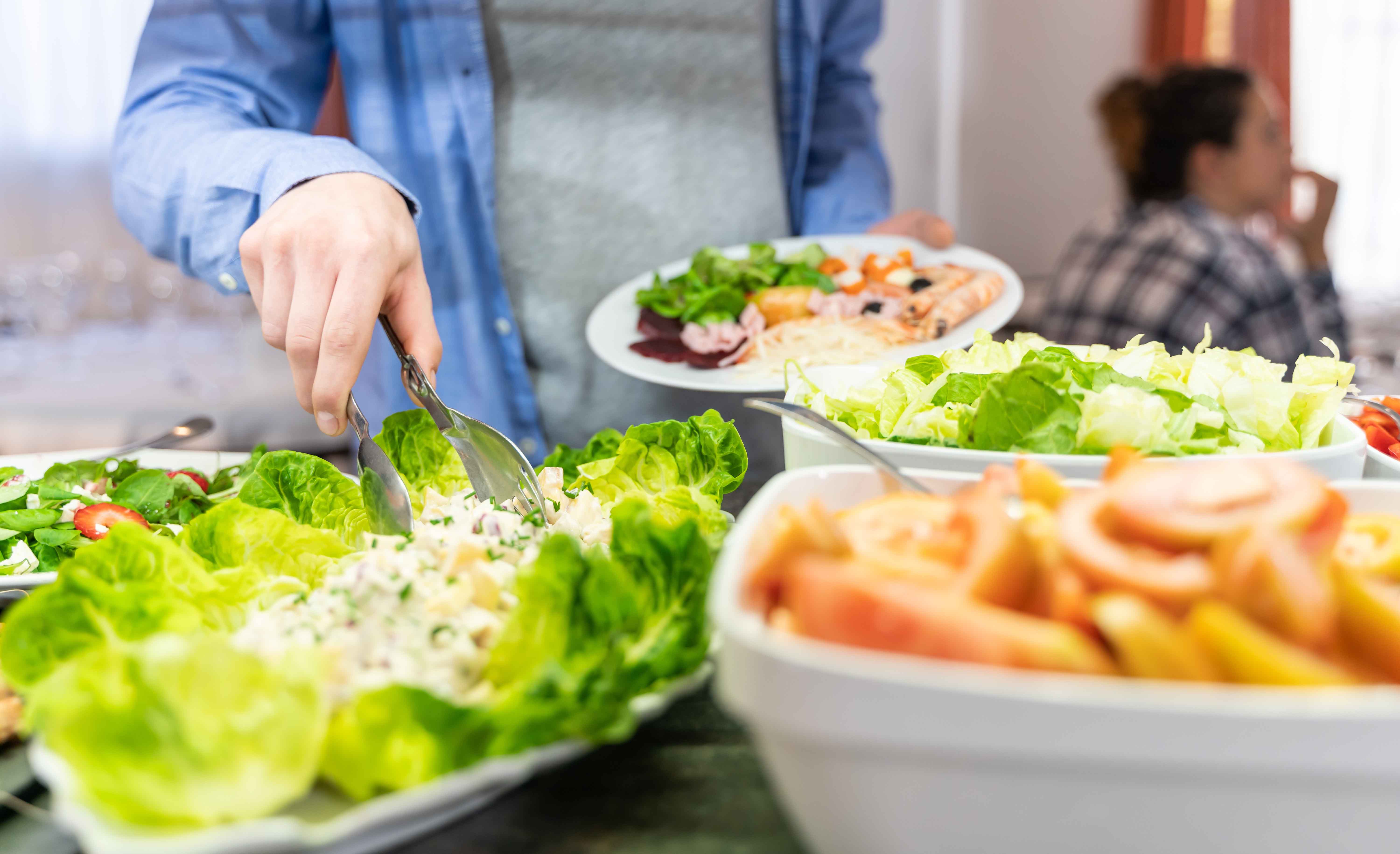 person getting salad at a salad bar