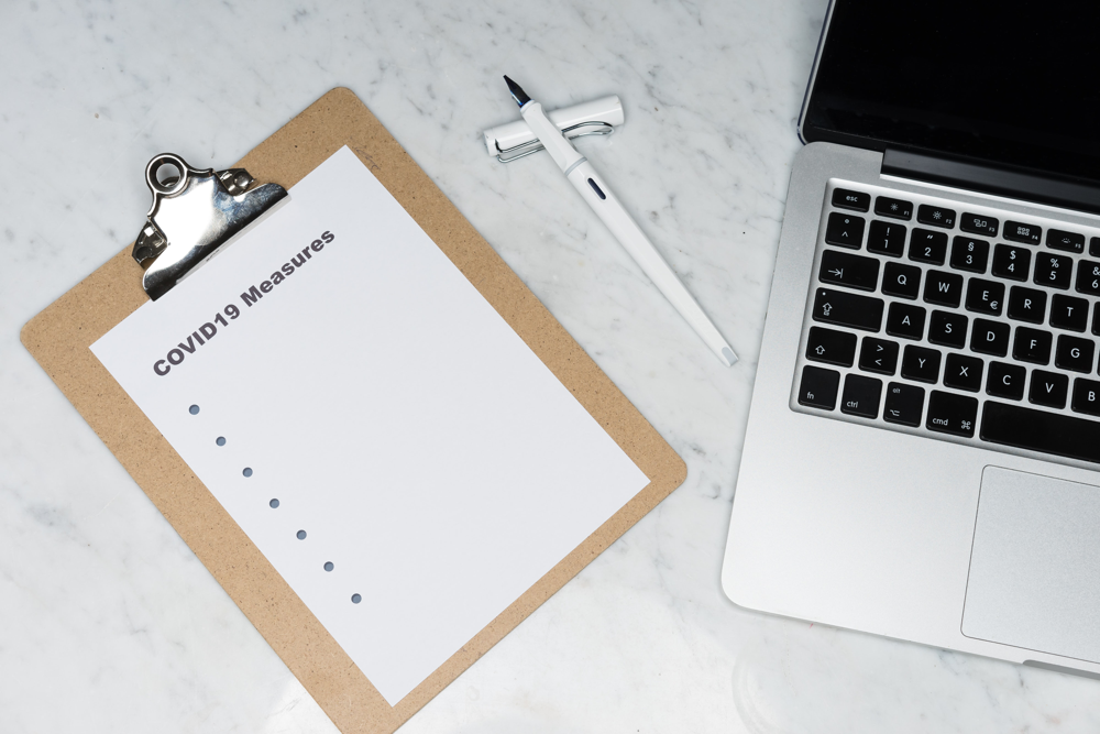 clipboard with Covid-19 Measures list next to laptop