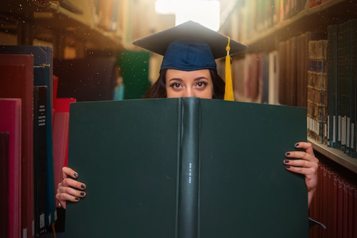 graduating student holding book in library