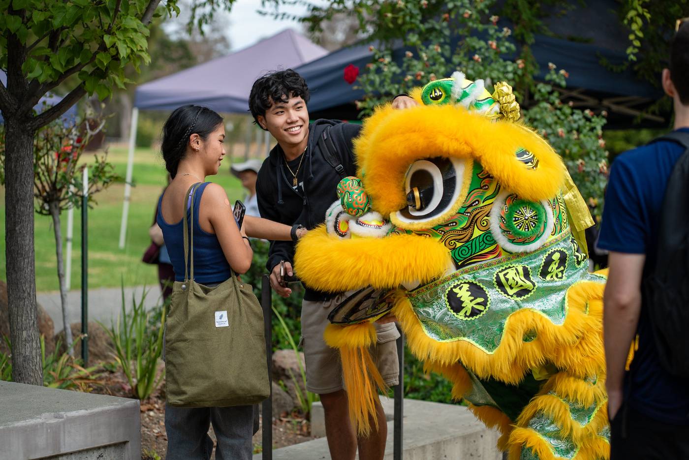 two students interacting with a cultural dancing lion