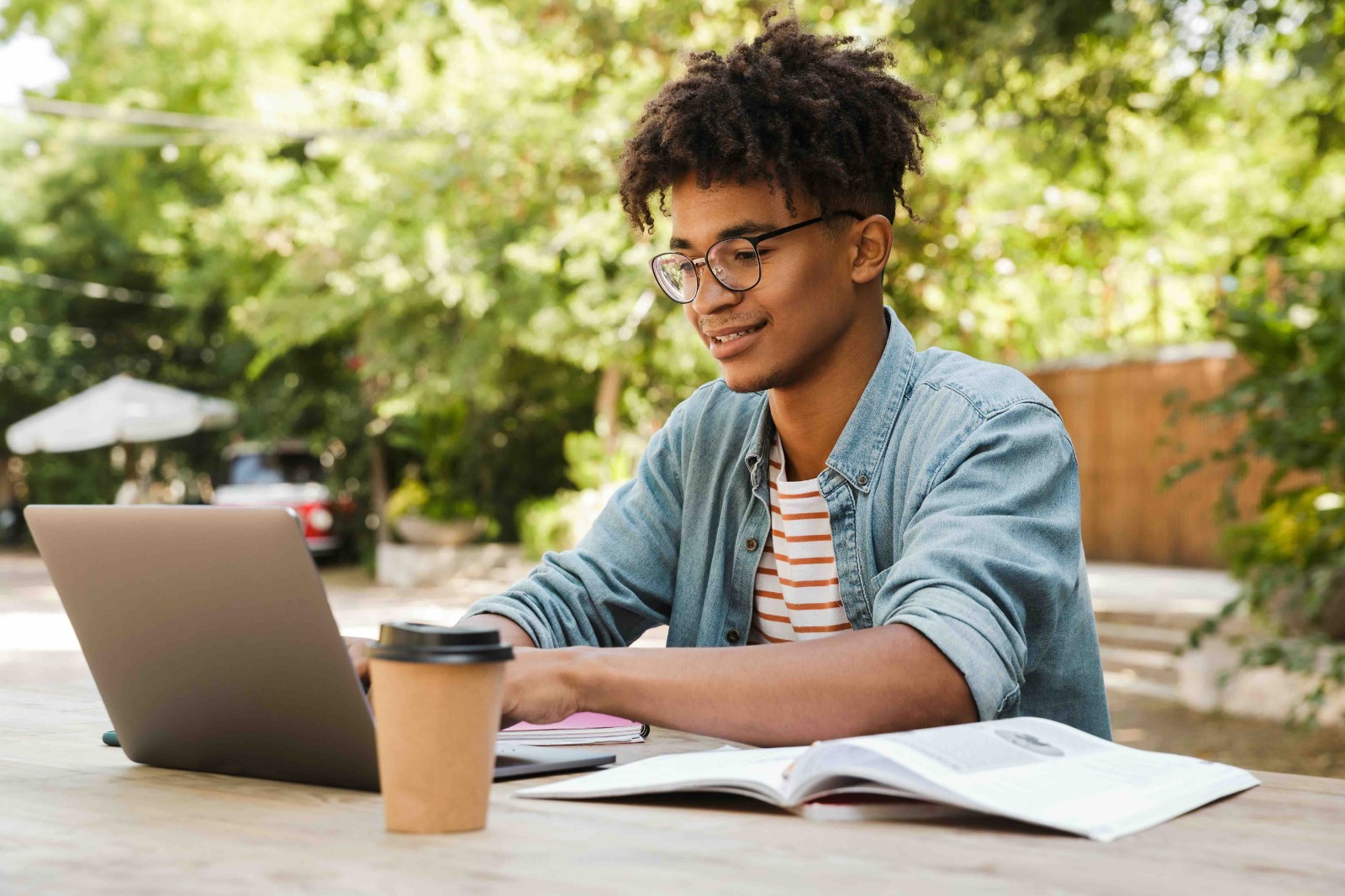 african american student wearing glasses doing work on his laptop