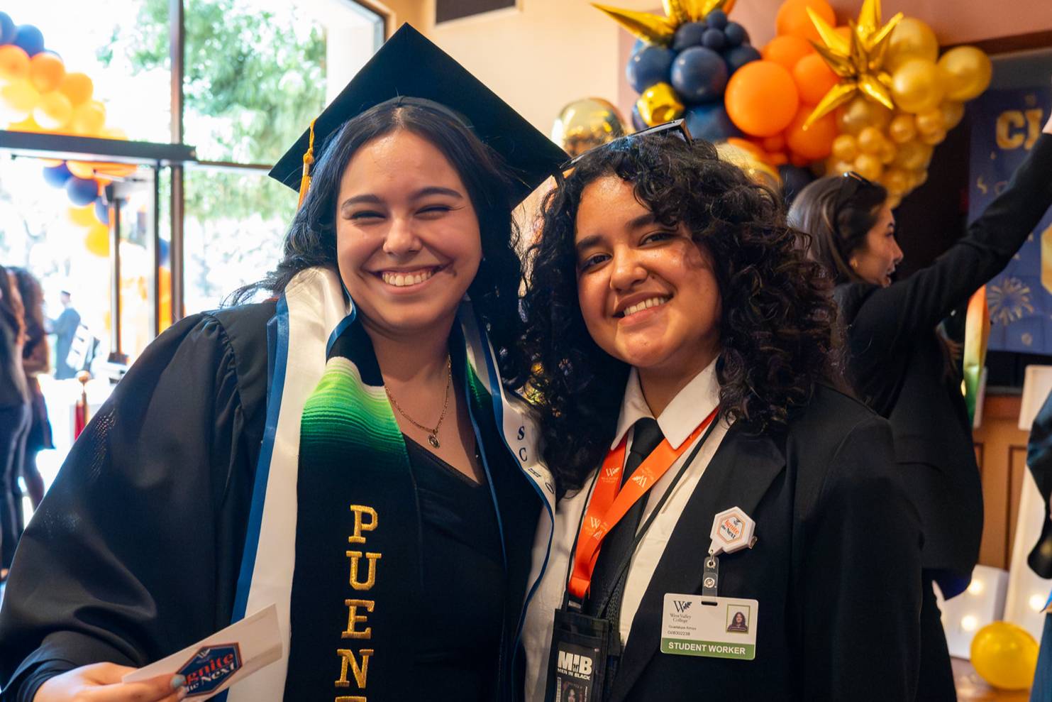 a puente graduate wearing a cap and gown with another student