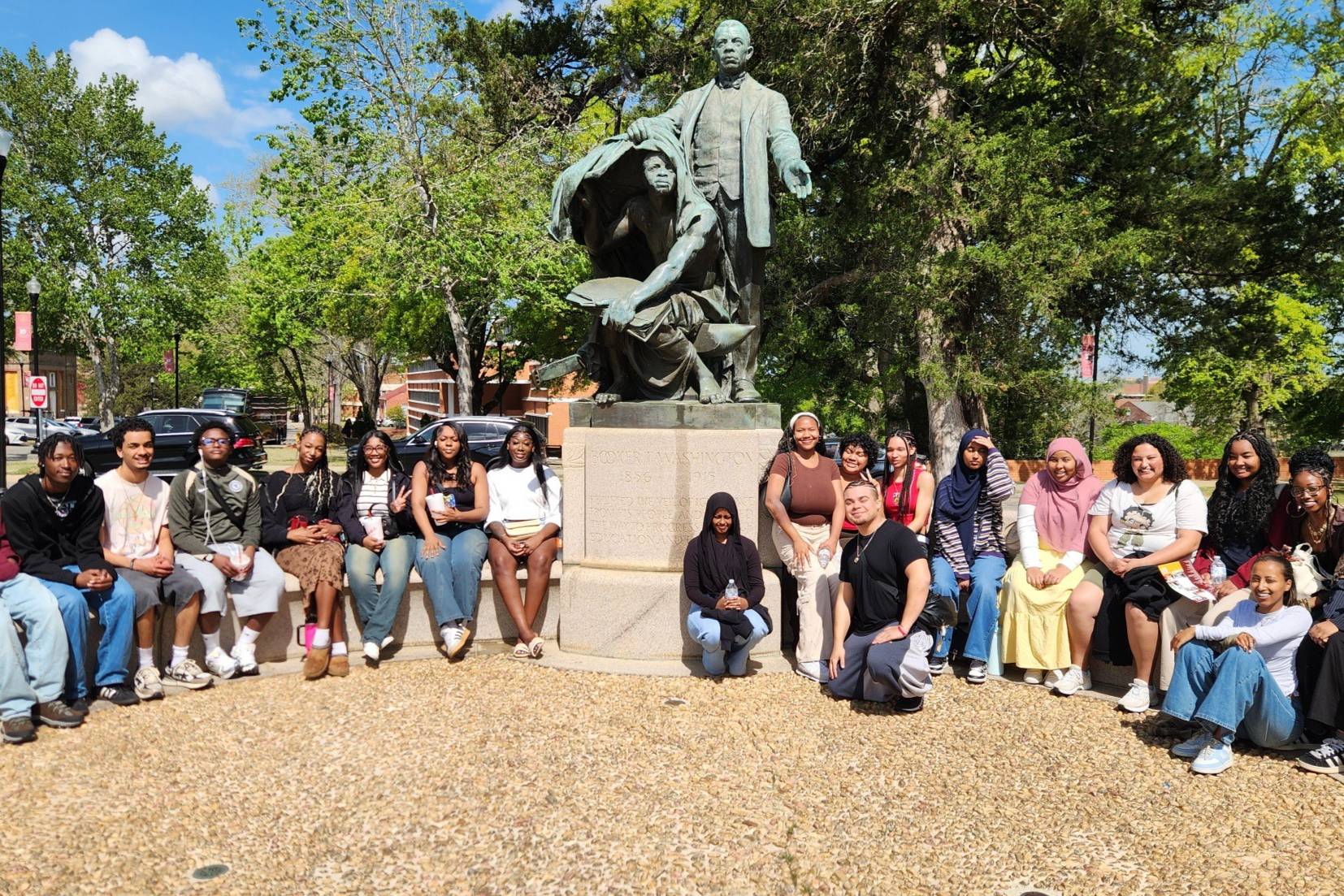 umoja students sitting around a green historical figure statue