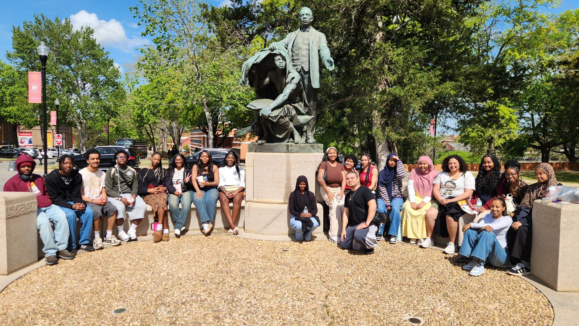 umoja students sitting around a green historical figure statue