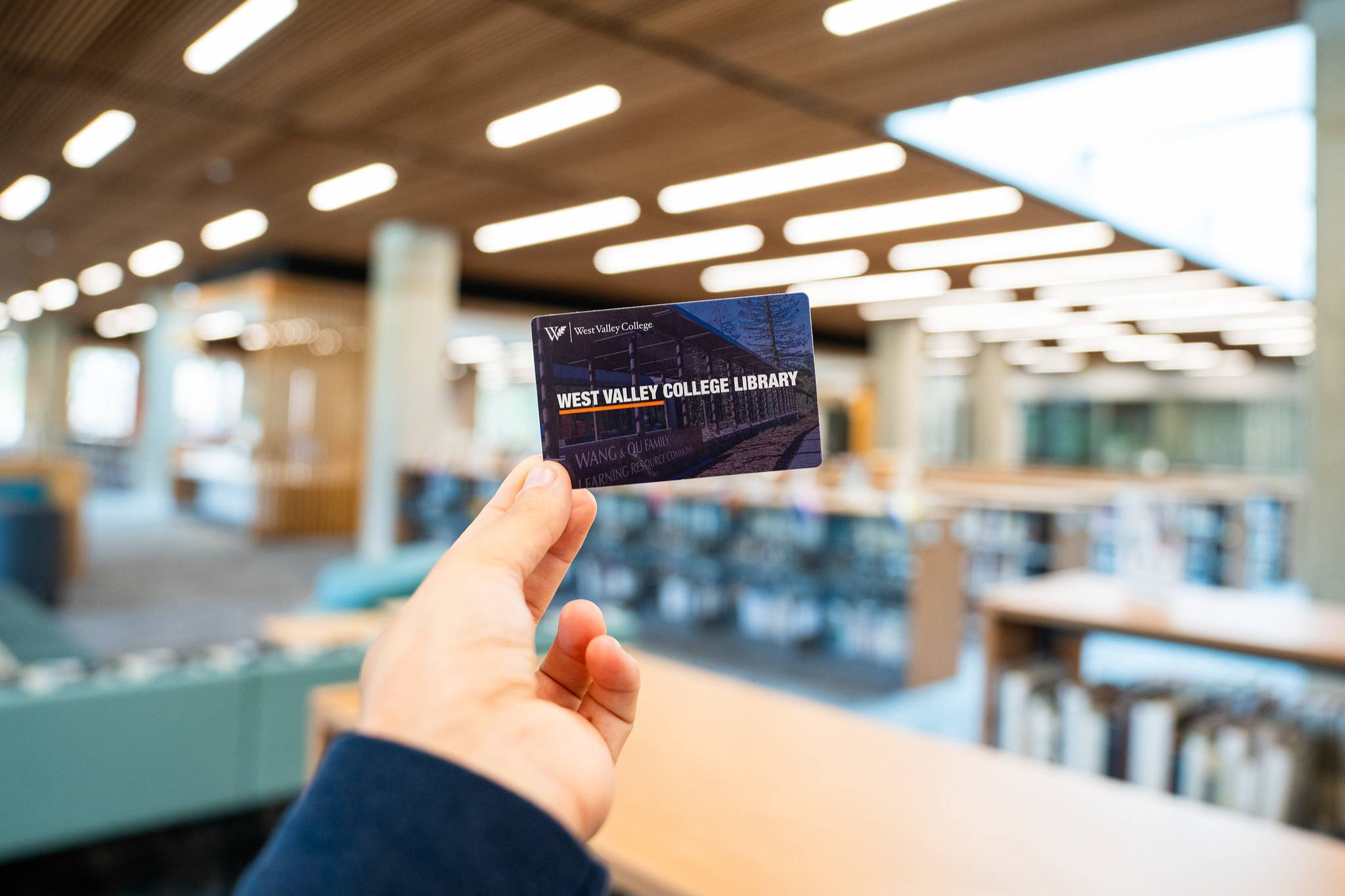 hand holding library card with the library space in the background