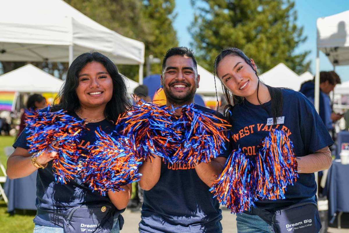 student ambassadors holding orange and blue pom poms at the spring block party