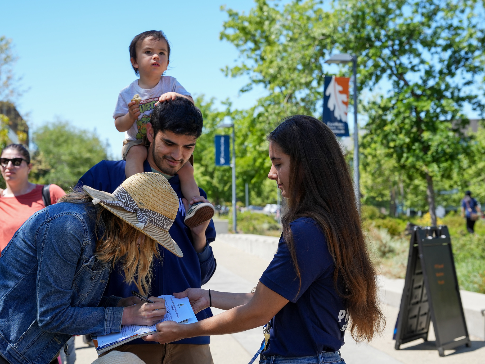 Bring Your Child to WVC Day parents with their child on shoulders signing paper