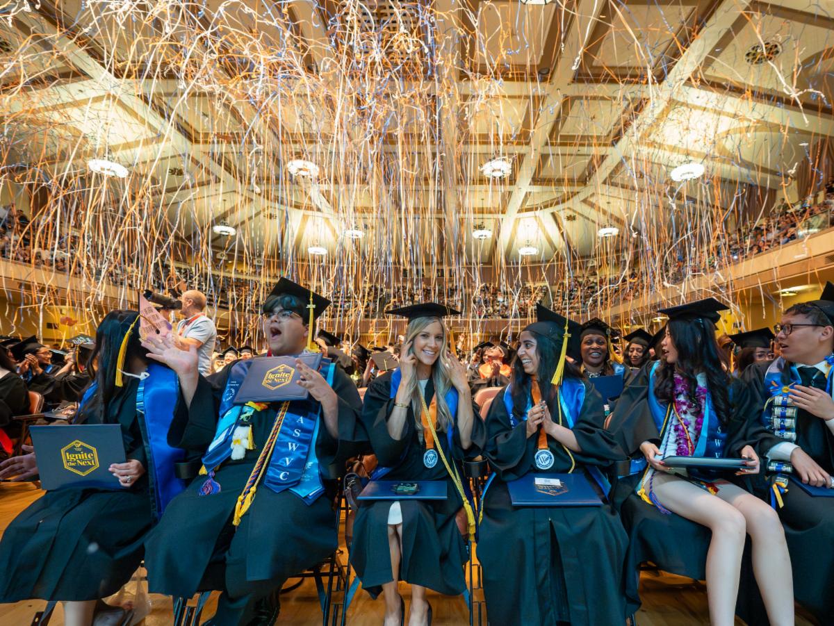 students wearing caps and gowns with streamers above their heads