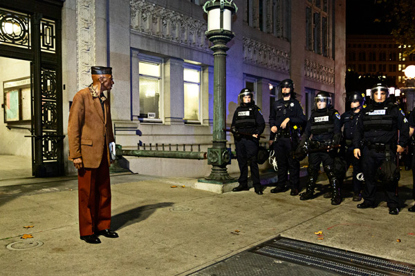 Older gentleman in suit facing many cops