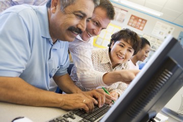 Multiple adults hovering around computer