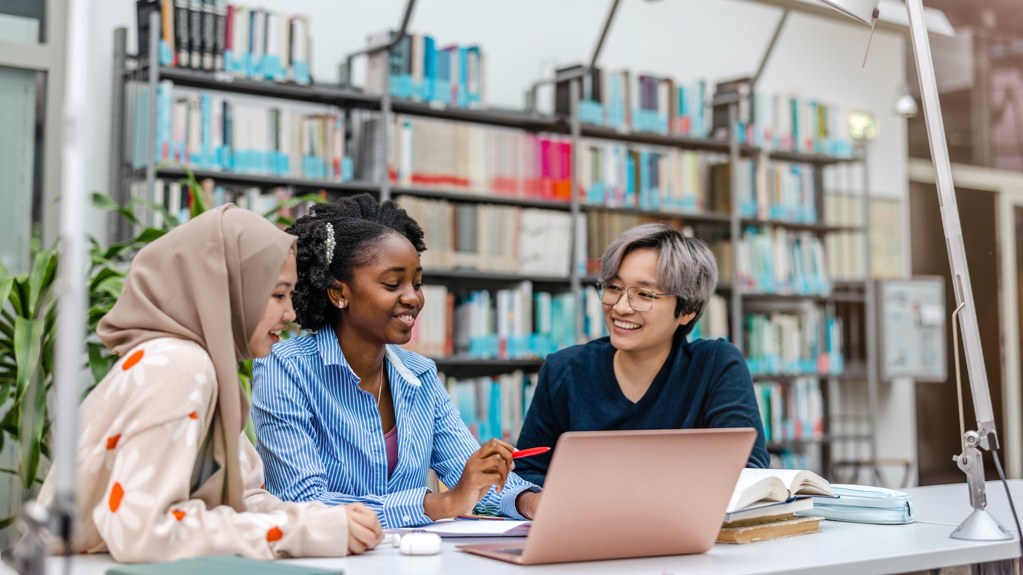 students at a table, talking in the library