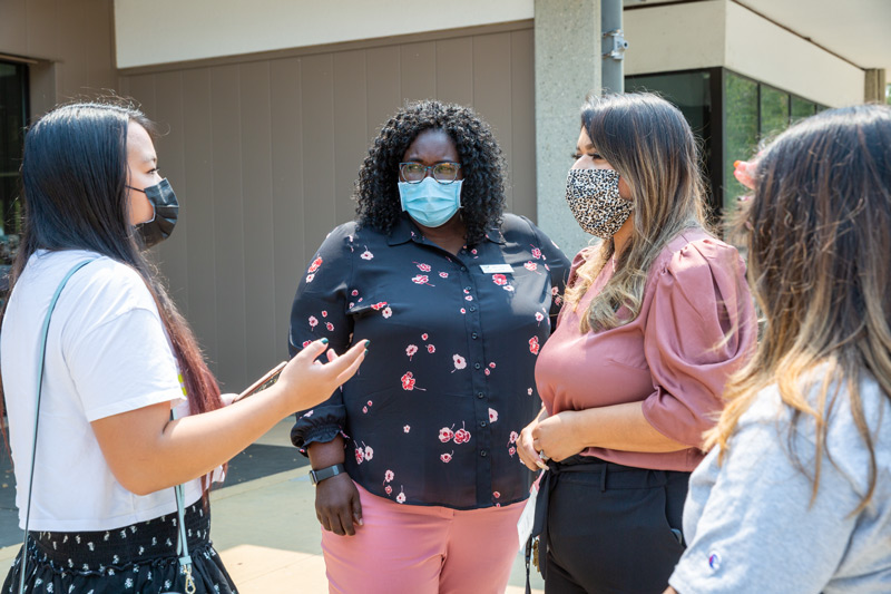 Masked women administrators talking to students, also with masks